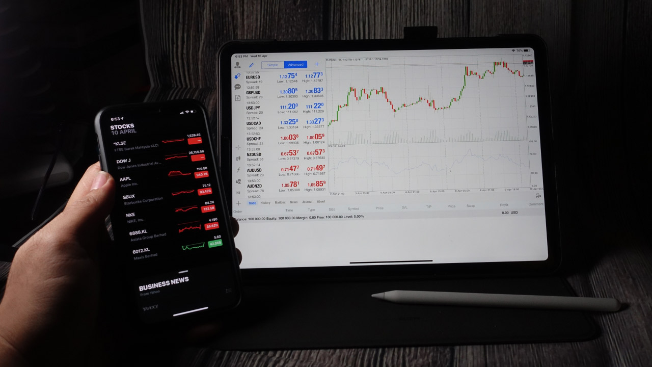 How to Check Your Trade History in MT5, a person holding a smartphone displaying stock market data.