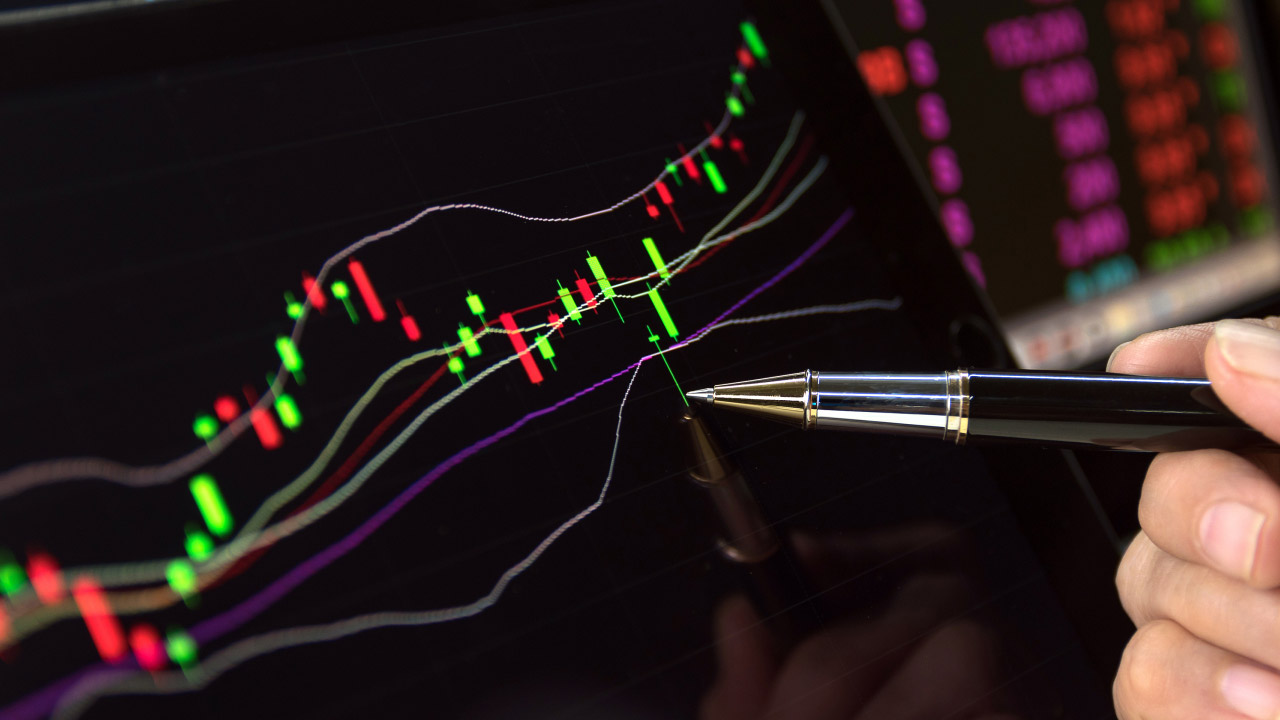 A close-up of a trader analyzing a candlestick chart with Bollinger Bands on a digital screen, using a pen to point at a specific price movement, illustrating "How to Study Your Losses to Realize Gains."